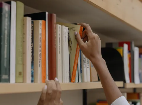 person grabbing a book from a library shelf